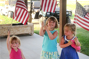 Three little girls waving American flags